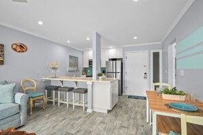 A modern kitchen with white cabinets, a central island, and a dining area with a wooden table and chairs.