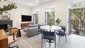 Un salon moderne avec un canapé, une table à manger ronde et un téléviseur fixé au mur.
