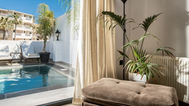 Un balcon avec une piscine, un coin salon confortable et des plantes en pot.
