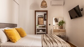 Une chambre à coucher comprenant un lit, une table de chevet, un miroir, une télévision et un luminaire suspendu.