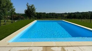 A rectangular swimming pool with clear blue water, surrounded by a tiled deck and a grassy area with trees. - Peace & tranquillity in the heart of the Dordogne (Lempzours)
