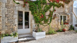 A stone building with a wooden door and windows, surrounded by gravel and potted plants. - Peace & tranquillity in the heart of the Dordogne (Lempzours)