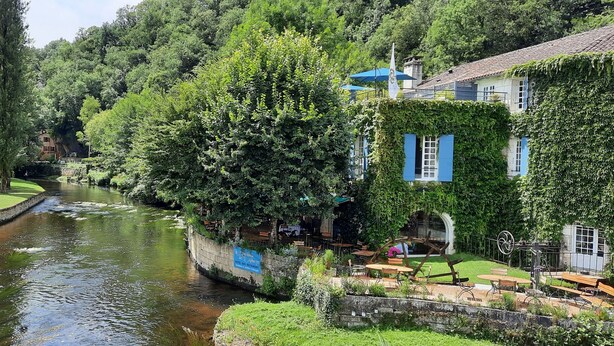 A riverside hotel with outdoor seating, a stone pathway, and lush greenery. - Peace & tranquillity in the heart of the Dordogne (Lempzours)