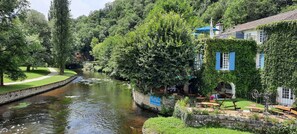 Ein Hotel am Flussufer mit Außenbereich, einem Steinweg und üppiger Bepflanzung.