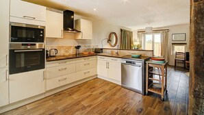 A modern kitchen with white cabinets, stainless steel appliances, and a wooden floor. - Peace & tranquillity in the heart of the Dordogne (Lempzours)