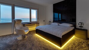 Un dormitorio moderno con una cama grande, un escritorio y una silla, con vistas al océano.