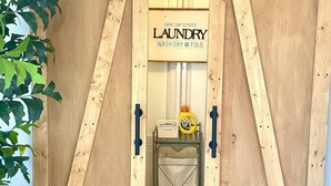Una puerta corredera de madera con un letrero que dice "Same Day Service Laundry Wash Dry & Fold" y un carro de lavandería en su interior.
