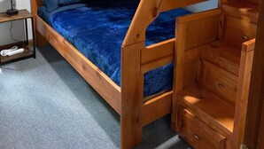 A bunk bed with a wooden frame and blue bedding. There is a small table with a lamp beside the bed. - Outlaw Lodge (Hatfield 1st Floor) ATV,SXS Offroad (Iaeger)