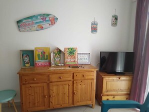 Un meuble en bois avec des tiroirs, une planche de surf encadrée et un téléviseur posé sur un meuble.