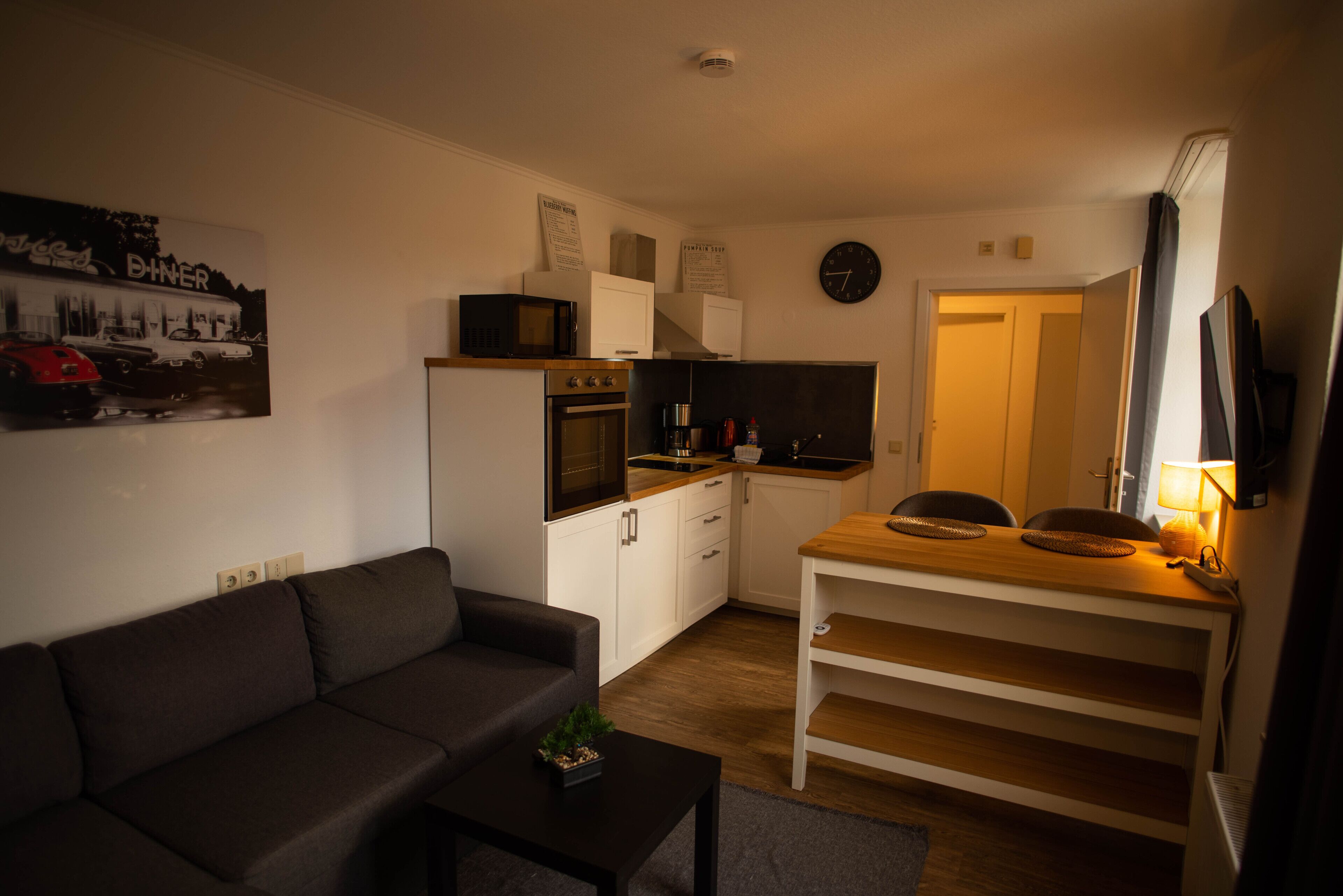 A compact living space with a sofa, a small table, a kitchenette, and a dining area.