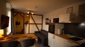 A compact kitchen with a wooden countertop, a built-in oven, and a microwave. There is a dining area with a table and chairs.