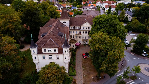 An aerial view of a large, historic building with multiple towers and a well-maintained garden.