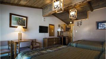 A cozy room with a bed, a desk with a lamp, a TV, and wooden walls.