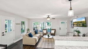 Ein modernes Wohnzimmer mit einer Couch, Sesseln, einem Couchtisch und einer Küchenzeile mit Marmorarbeitsplatte.