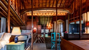 L’intérieur d’un chalet accueillant, avec un plafond en bois, un lit doté d’une table de chevet, un bureau avec une lampe et un téléviseur.