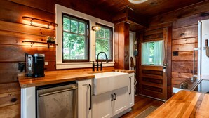 Une cuisine avec des meubles en bois, un évier blanc et une machine à café.