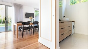 A modern kitchen with a built-in washing machine, a dining area with a table and chairs, and a large window providing natural light.