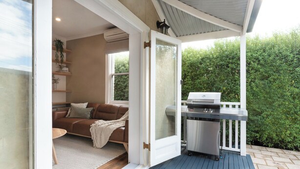 An open door leading to a living room with a sofa and a grill outside. - Walter Cottage: As Cosy as it is Convenient (South Launceston)