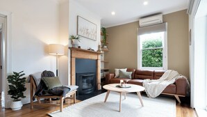 A living room with a fireplace, a sofa, a coffee table, and a lamp. - Walter Cottage: As Cosy as it is Convenient (South Launceston)