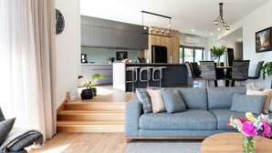 A modern living room with a grey sofa, wooden flooring, and a round coffee table. - Impressively Spacious, Modern & Convenient (Newstead)