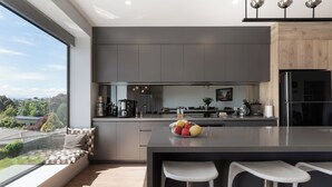 A modern kitchen with a large island, bar stools, and a view of the city. - Impressively Spacious, Modern & Convenient (Newstead)