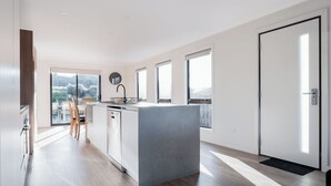 A modern kitchen with a central island, large windows, and a view of the outdoors. - Modern & Convenient in Newstead (Newstead)