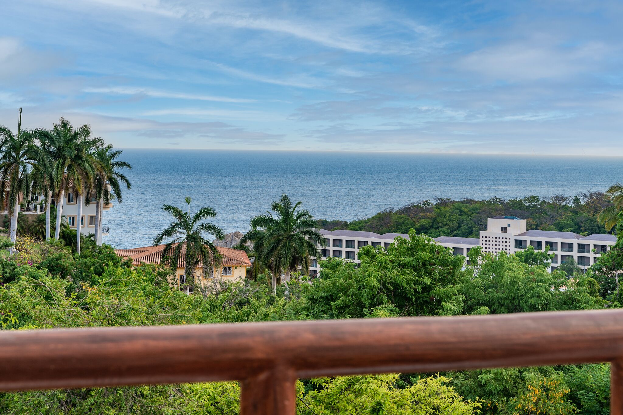 Vista costera con un conjunto de edificios, palmeras y cielo despejado.