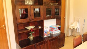 A wooden cabinet with glass doors, a vase with a flower, and a stack of board games. - Peaceful holiday apartment on a small farm, Tørberget in Trysil (Innlandet)