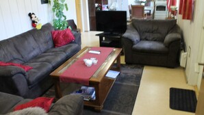 A living room with a sofa, a coffee table, and a television. - Peaceful holiday apartment on a small farm, Tørberget in Trysil (Innlandet)