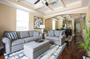 A spacious living room with a gray sectional sofa, a matching ottoman, and a patterned rug. - Big Easy GEM of New Orleans (New Orleans)