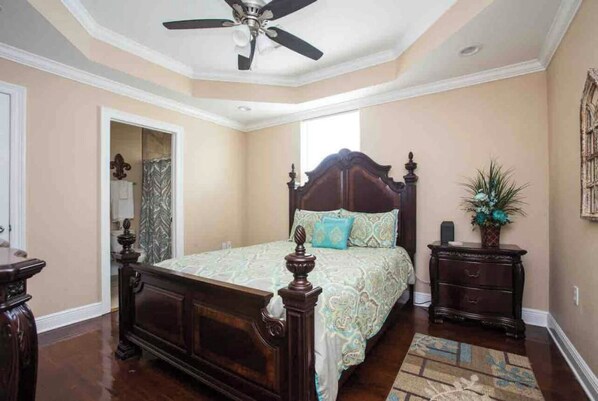 A bedroom with a wooden bed, a ceiling fan, a nightstand, and a window. - Big Easy GEM of New Orleans (New Orleans)