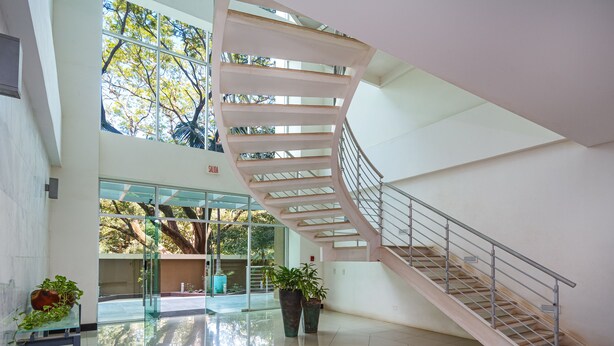 Un interior moderno con una escalera de caracol, puertas de cristal que dan a un espacio exterior y plantas en macetas.