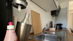 Une cuisine moderne équipée d’un évier en acier inoxydable, d’une machine à café et d’un four à micro-ondes.