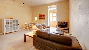 A living room with a sofa, a dining table, and a TV.
