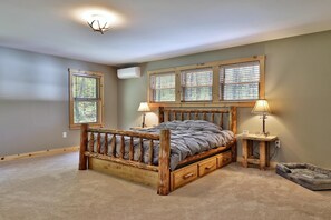 Cozy retreat with a rustic bed, two windows, and a bedside table.