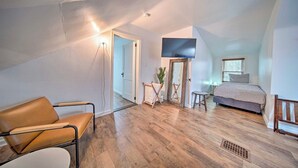 Une chambre de style loft moderne, dotée d’un grand lit, d’un téléviseur fixé au mur et d’un plancher en bois.