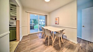 Un coin repas avec une table et des chaises, une porte-fenêtre coulissante donnant sur un patio, et un espace cuisine équipé de placards et d’un four à micro-ondes.