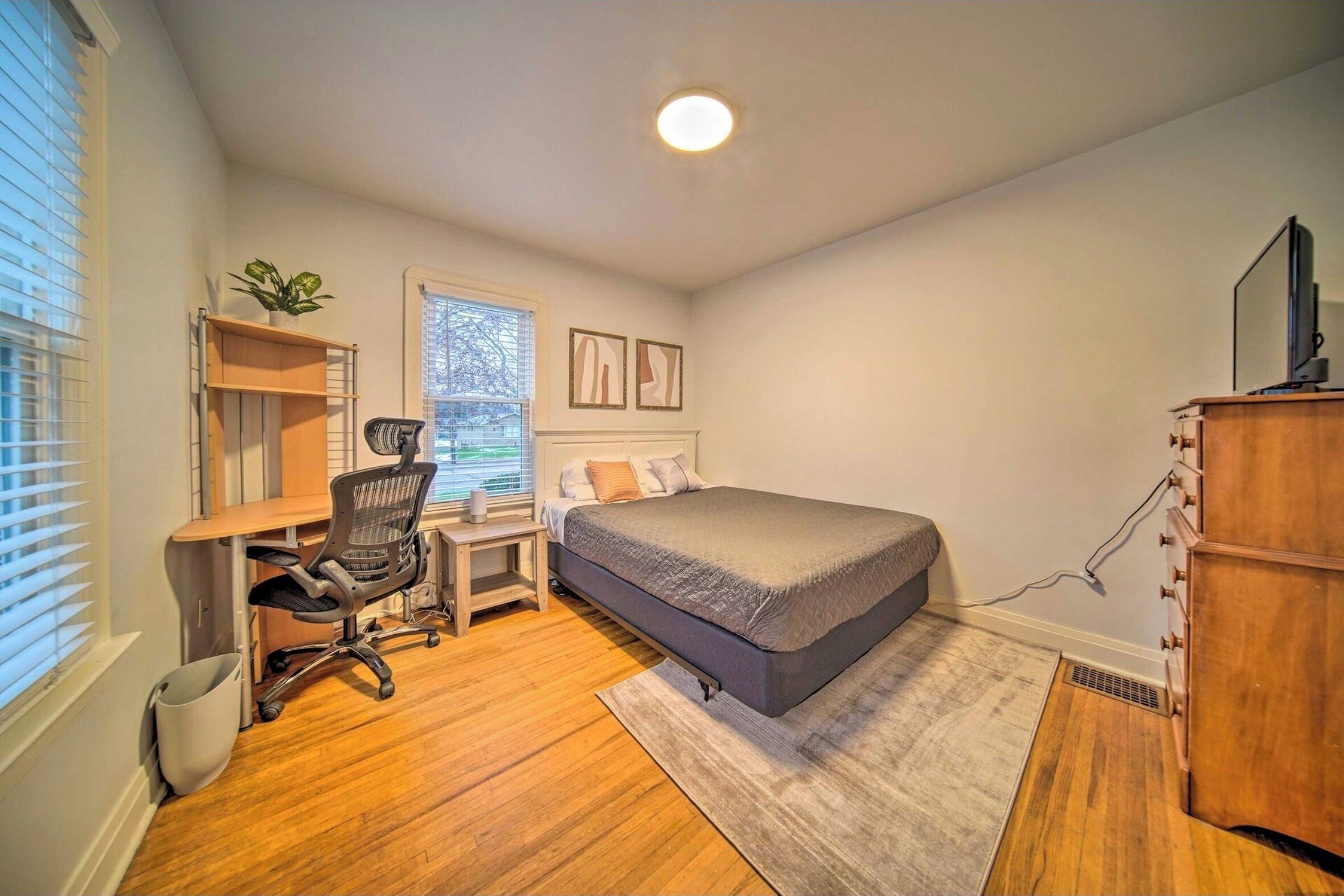 Un dormitorio con cama, escritorio, silla y cómoda.