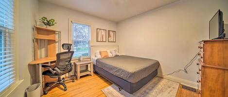 Un dormitorio con cama, escritorio, silla y cómoda.