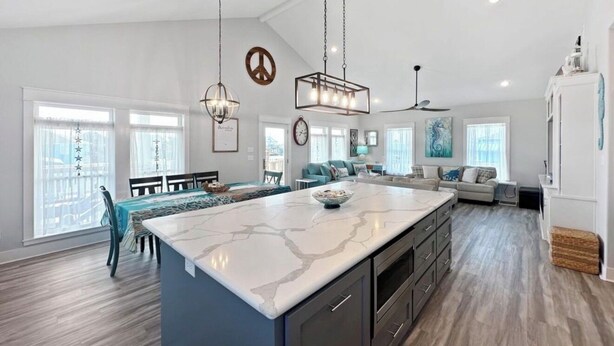 A spacious kitchen with a large island, modern pendant lights, and a view of the living area. - 3min walk to beach,hot tub, b-ball, pet friendly, parking for RV’s (Bolivar Peninsula)