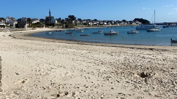 Une plage de sable avec des bateaux et une église en arrière-plan.