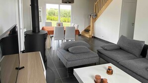 Un salon moderne avec une cheminée, un canapé gris et un coin repas comprenant une table et des chaises.