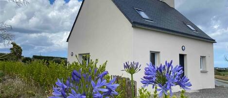 Une maison de plain-pied avec un toit en pente, une cheminée et une petite fenêtre.