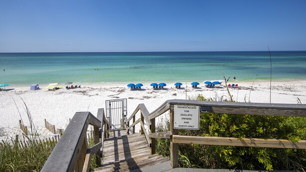 A wooden staircase leading to a beach with clear turquoise water, umbrellas, and a sign indicating private access for seacliff owners and guests. - Waterview - Gulf side condominium, Walkable to restaurants, near 30A Bike Path (Blue Mountain Beach)