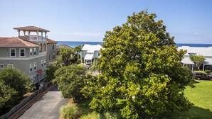 A multi-story building with a rooftop pavilion, surrounded by lush greenery and a clear view of the ocean. - Waterview - Gulf side condominium, Walkable to restaurants, near 30A Bike Path (Blue Mountain Beach)
