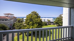 A balcony with a view of a residential area, including houses and a tree. - Waterview - Gulf side condominium, Walkable to restaurants, near 30A Bike Path (Blue Mountain Beach)