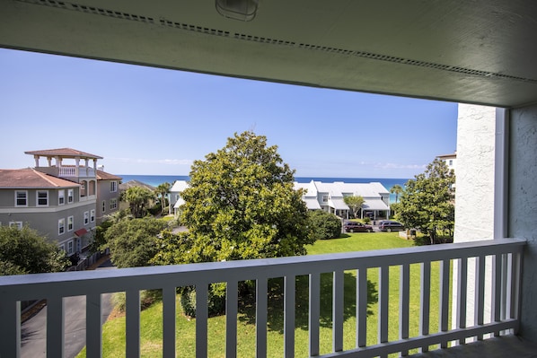 A balcony with a view of a residential area, including houses and a tree. - Waterview - Gulf side condominium, Walkable to restaurants, near 30A Bike Path (Blue Mountain Beach)