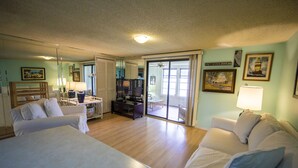 A hotel room with a large bed, a sofa, a desk with a lamp, a television, and a sliding glass door leading to a balcony. - Waterview - Gulf side condominium, Walkable to restaurants, near 30A Bike Path (Blue Mountain Beach)