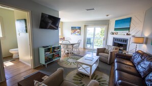 A living room with a sofa, chairs, a coffee table, a fireplace, and a TV mounted on the wall. - Waterview - Gulf side condominium, Walkable to restaurants, near 30A Bike Path (Blue Mountain Beach)
