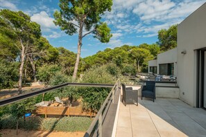 Une terrasse extérieure moderne, dotée d’une plateforme en bois, d’une rambarde en métal et d’un espace salon avec des chaises.